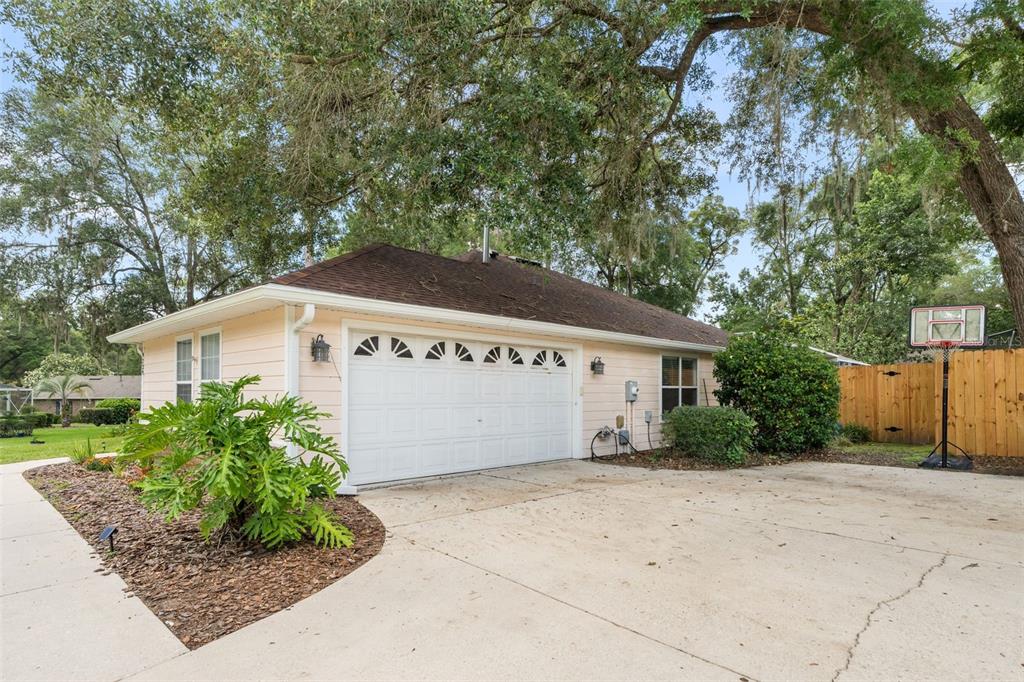 A detached garage with a white door, light-colored siding, and a concrete driveway — 9239 NW 16TH PLACE, GAINESVILLE, FL
