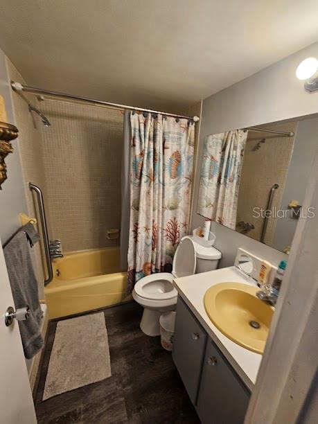 A bathroom features a yellow tub and sink, a patterned shower curtain, and dark flooring — 4565 DUHME ROAD UNIT 207, ST PETERSBURG, FL