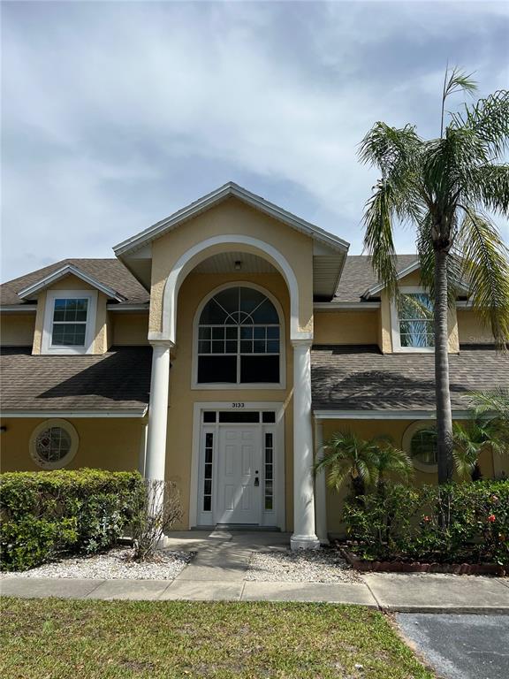 A long, open-concept living area features gray wood-look flooring and leads to a kitchen — 3133 ENCLAVE COURT, KISSIMMEE, FL