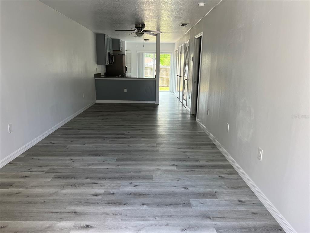 A kitchen features stainless steel appliances, gray cabinets, and light wood-look flooring — 3133 ENCLAVE COURT, KISSIMMEE, FL