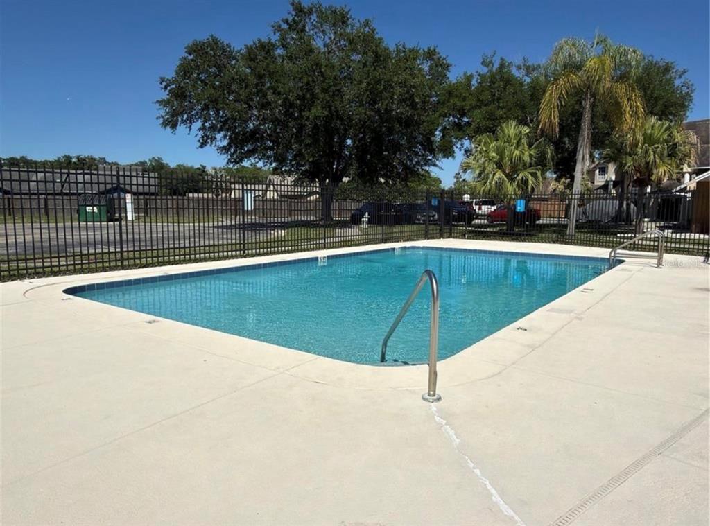 A rectangular swimming pool with a metal handrail sits on a concrete deck — 3133 ENCLAVE COURT, KISSIMMEE, FL