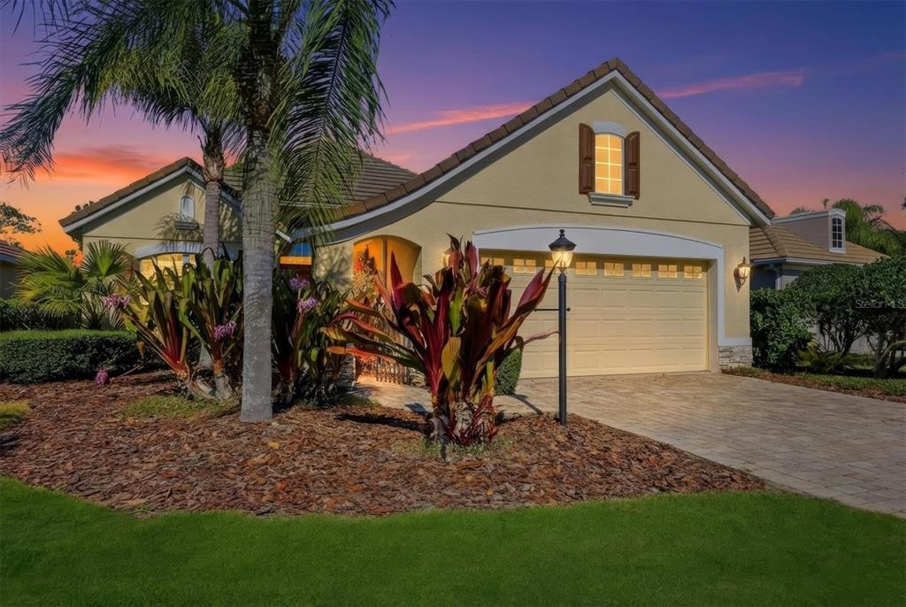 A single-story house with a beige exterior, a two-car garage, and a landscaped front yard — 7478 EDENMORE STREET, LAKEWOOD RANCH, FL