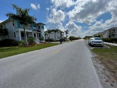 A street view shows residential houses with palm trees under a blue, cloudy sky — 310 W HENRY STREET, PUNTA GORDA, FL