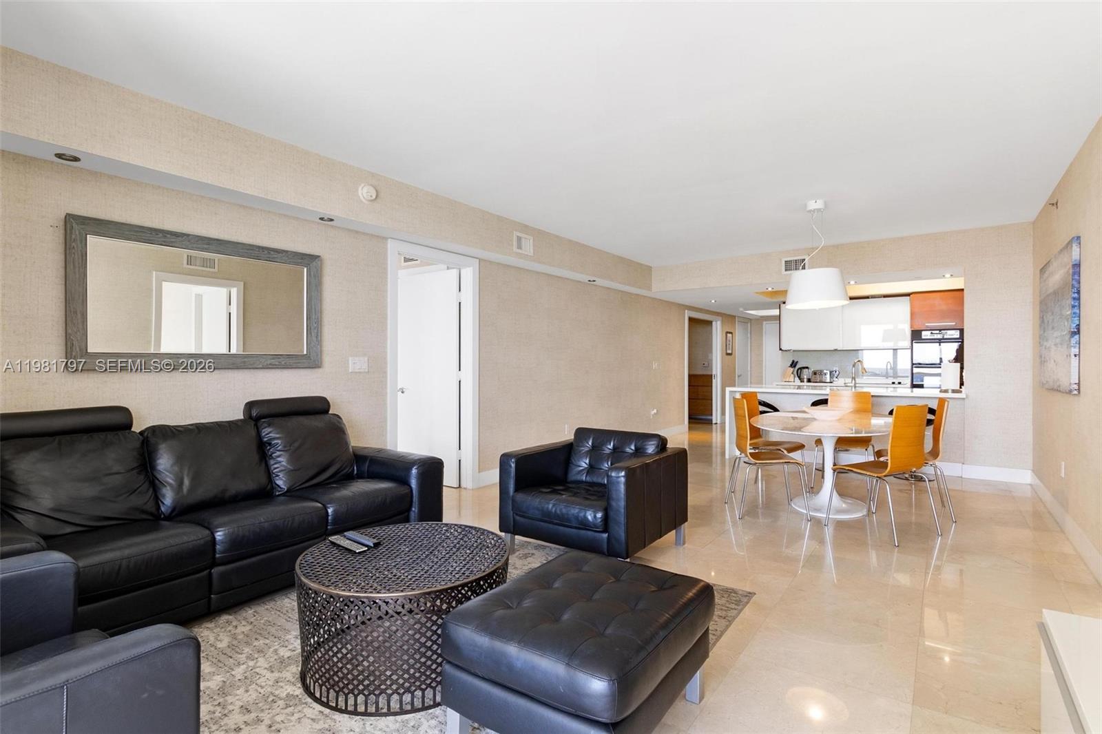 A living room with black leather furniture, a round coffee table, and an adjacent dining area — 1830 S Ocean Dr # 2904, Hallandale Beach FL 33009, HALLANDALE BEACH, FL