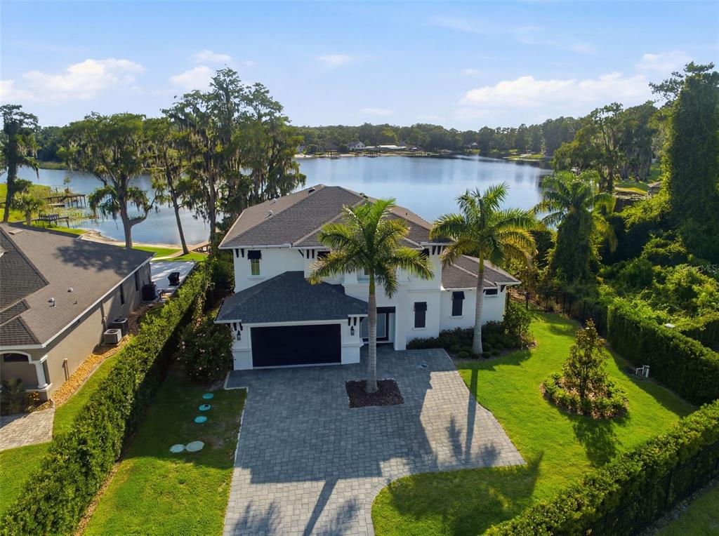 An aerial view of a two-story white house with a paved driveway and lakefront backyard — 17104 CRAWLEY ROAD, ODESSA, FL