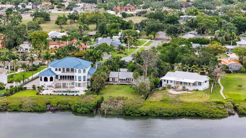 An aerial view shows a large blue-roofed house with a pool next to two smaller homes — 7538 WESTMORELAND DRIVE, SARASOTA, FL