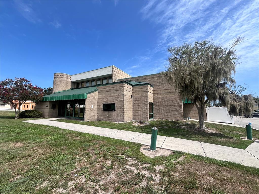 A tan masonry commercial building features a green metal awning and a curved corner section — 450 W MAIN STREET 2nd Floor, BARTOW, FL