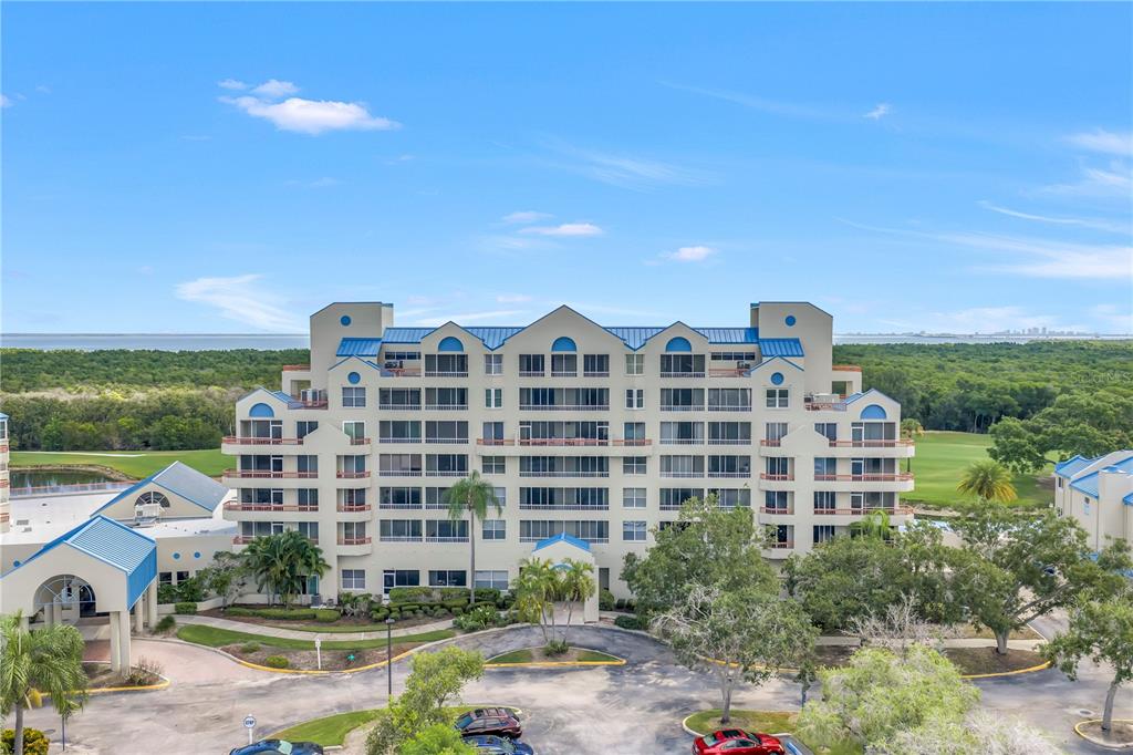 An exterior view of a multi-story residential building with balconies surrounded by trees and landscaping — 2333 FEATHER SOUND DRIVE UNIT C201, CLEARWATER, FL