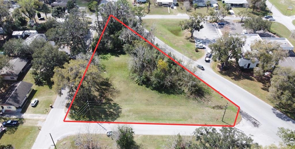 An aerial view shows a triangular, grassy vacant lot outlined in red between two roads — 5810 SE ABSHIER BOULEVARD, BELLEVIEW, FL