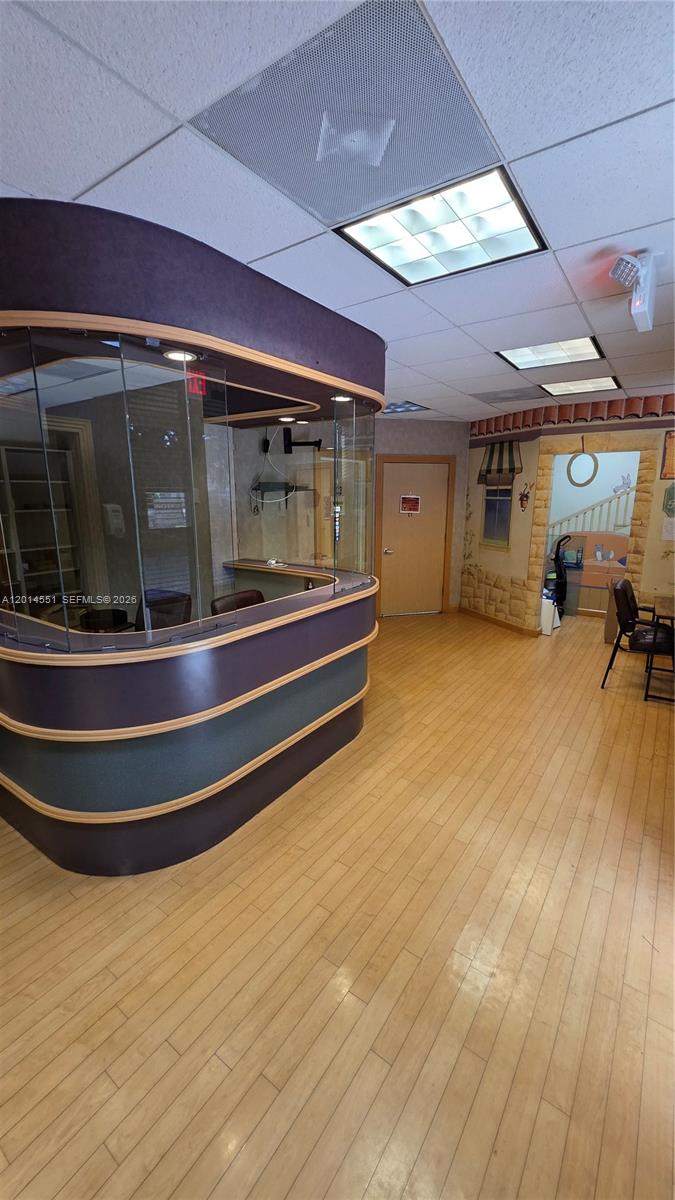 A reception area features a curved glass desk, light wood flooring, and a muraled wall — 5409 N State Road 7, Tamarac FL 33319, TAMARAC, FL