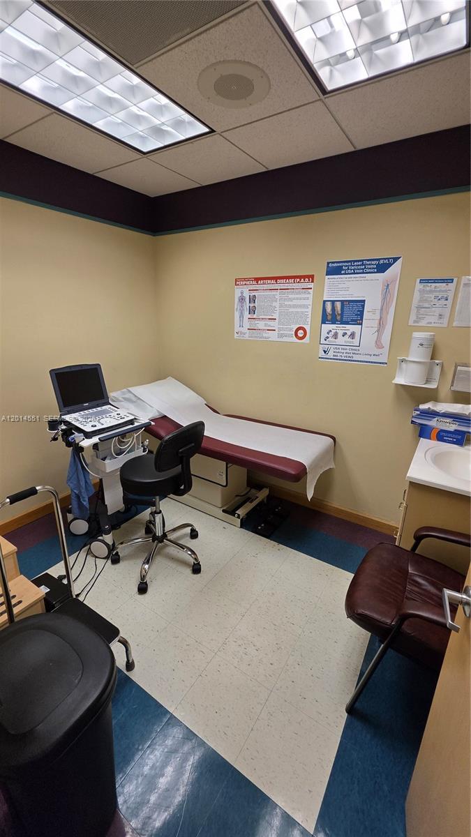 A medical examination room features an ultrasound machine, an exam table, and wall-mounted health posters — 5409 N State Road 7, Tamarac FL 33319, TAMARAC, FL
