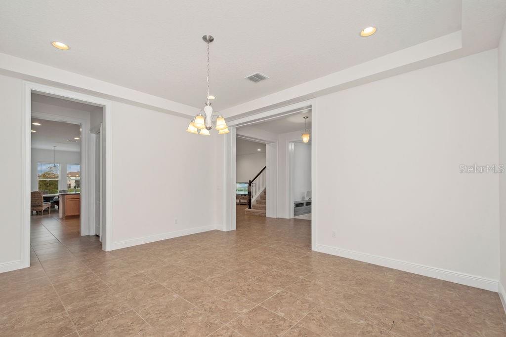 A dining room with tile flooring, a tray ceiling, and a chandelier — 17538 BLACK RAIL STREET, WINDERMERE, FL
