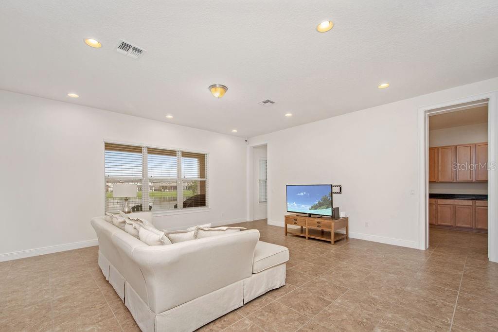 A living room with tile flooring, a white sofa, and a television on a stand — 17538 BLACK RAIL STREET, WINDERMERE, FL