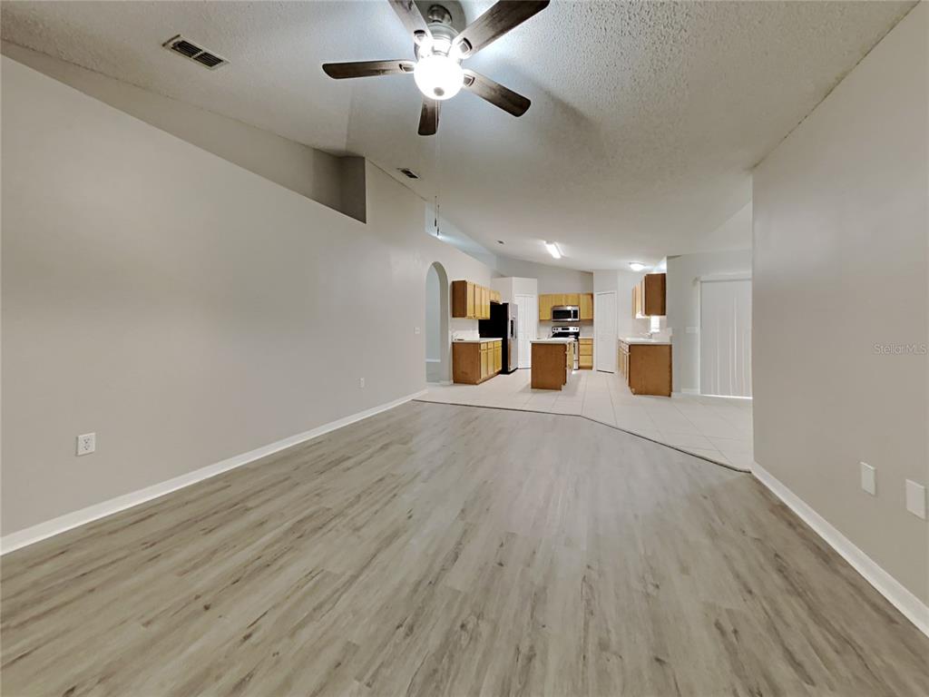 A living room with light wood-look flooring transitions to a tiled kitchen with oak cabinets — 508 CLOUDCROFT DRIVE, DELTONA, FL