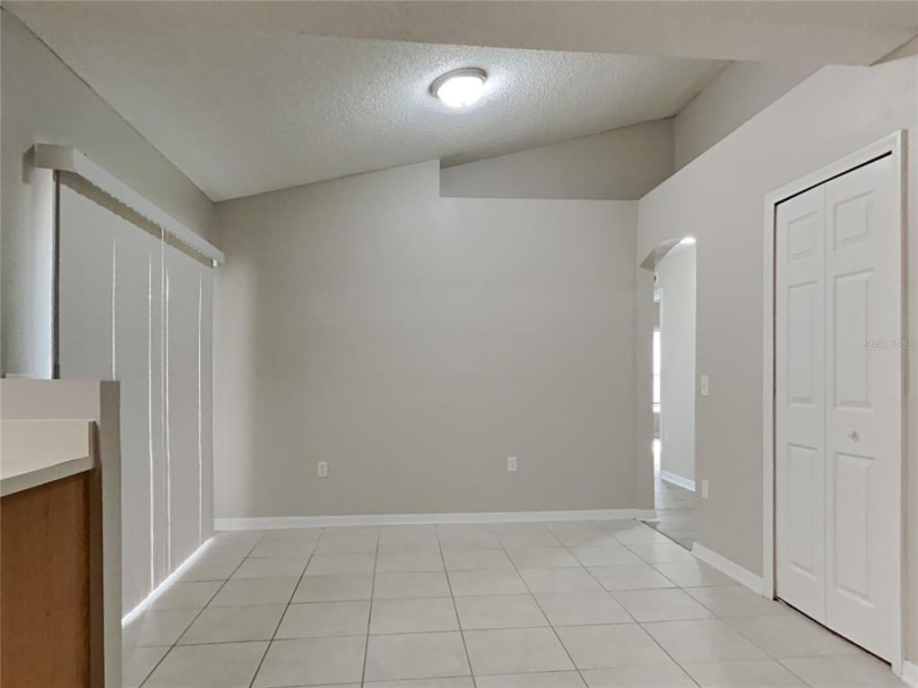 A dining area features light-colored tile flooring, a vaulted ceiling, and a white closet door — 508 CLOUDCROFT DRIVE, DELTONA, FL