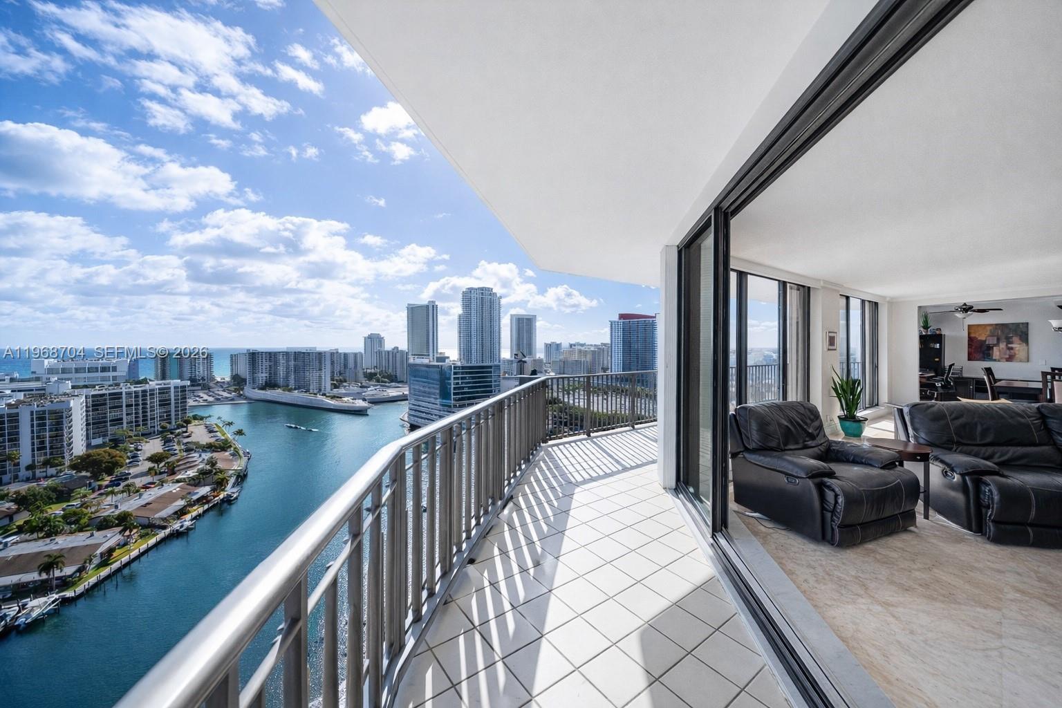 A balcony with tiled flooring overlooks a waterway and city skyline from a high-rise apartment — 300 Three Islands Blvd, Hallandale Beach FL 33009, HALLANDALE BEACH, FL
