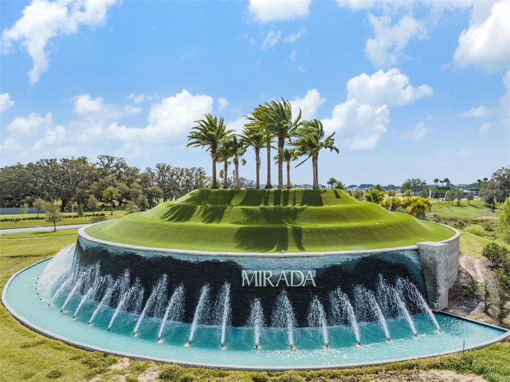 An aerial view of a circular fountain with a grassy mound and palm trees — 10412 FIELDSTONE MYRTLE WAY, SAN ANTONIO, FL