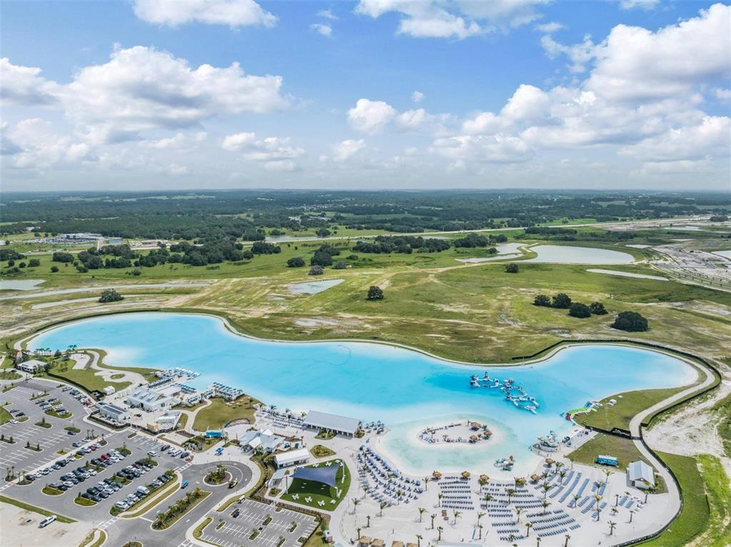 An aerial view shows a large, bright blue man-made lagoon surrounded by parking and landscaping — 10412 FIELDSTONE MYRTLE WAY, SAN ANTONIO, FL