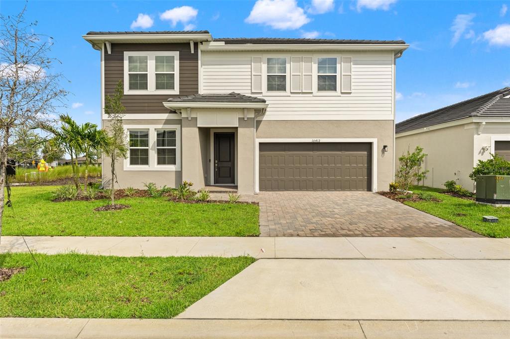 A two-story house with a brown garage, white siding, and a paved driveway — 10412 FIELDSTONE MYRTLE WAY, SAN ANTONIO, FL