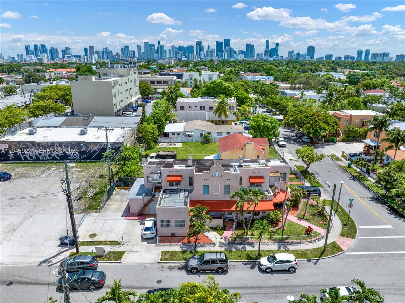 An aerial view shows a pink multi-unit building with orange awnings near a city skyline — 829 SW 19th Ave, Miami FL 33135, MIAMI, FL