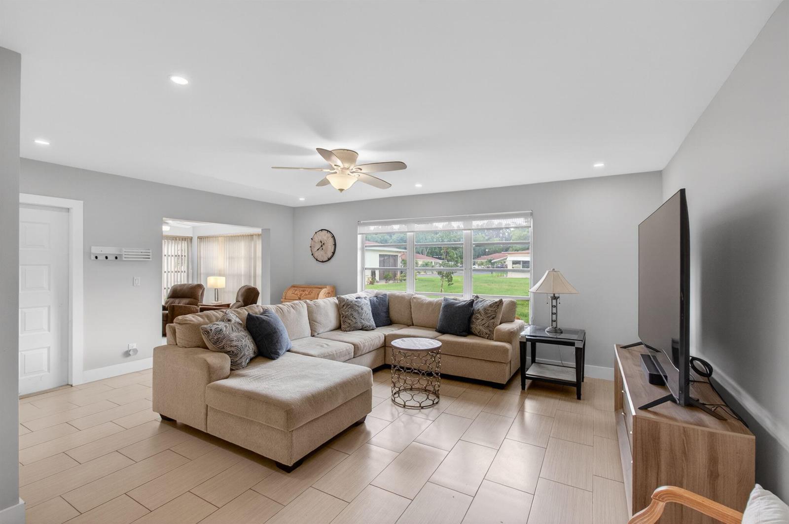 A living room features a large sectional sofa, tile flooring, and a television on a stand — 5250 NW 3rd Court # A, Delray Beach FL 33445, DELRAY BEACH, FL
