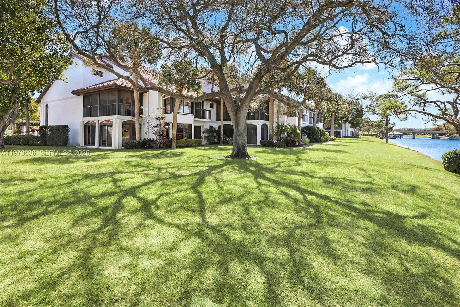 A modern living room features a white sectional sofa, a patterned rug, and an open kitchen — 16671 N Traders Crossing N # 121, Jupiter FL 33477, JUPITER, FL