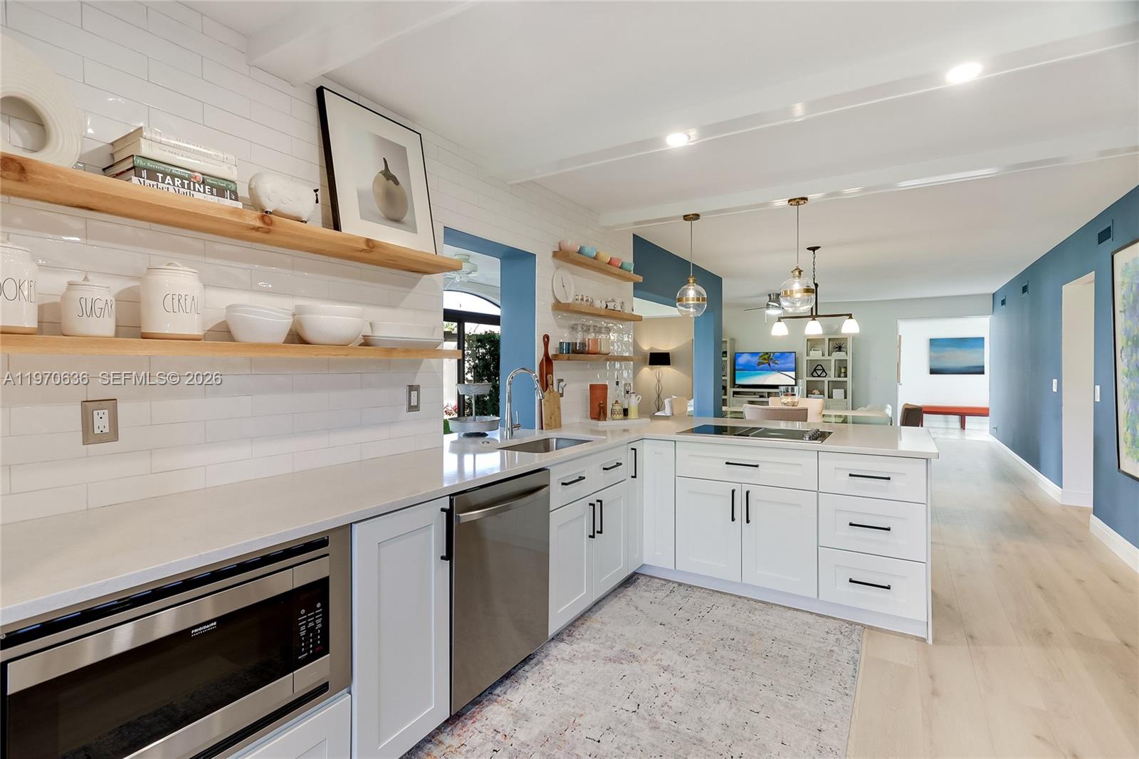 A modern kitchen features white cabinets, open wood shelving, and a stainless steel dishwasher — 16671 N Traders Crossing N # 121, Jupiter FL 33477, JUPITER, FL