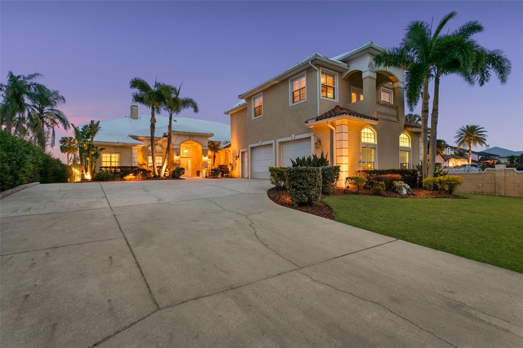 A two-story stucco house with a concrete driveway, palm trees, and a two-car garage — 4915 TROYDALE ROAD, TAMPA, FL