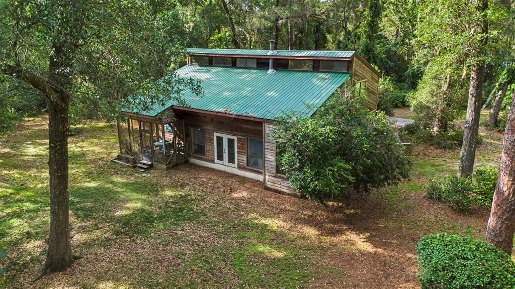An elevated view of a wooden house with a green metal roof in a forest — 2906 SE 36TH LANE, GAINESVILLE, FL