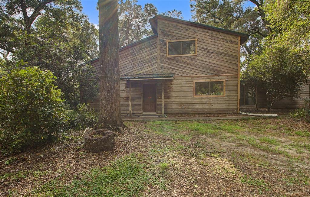 A two-story wooden house with a shed roof sits in a wooded yard — 2906 SE 36TH LANE, GAINESVILLE, FL