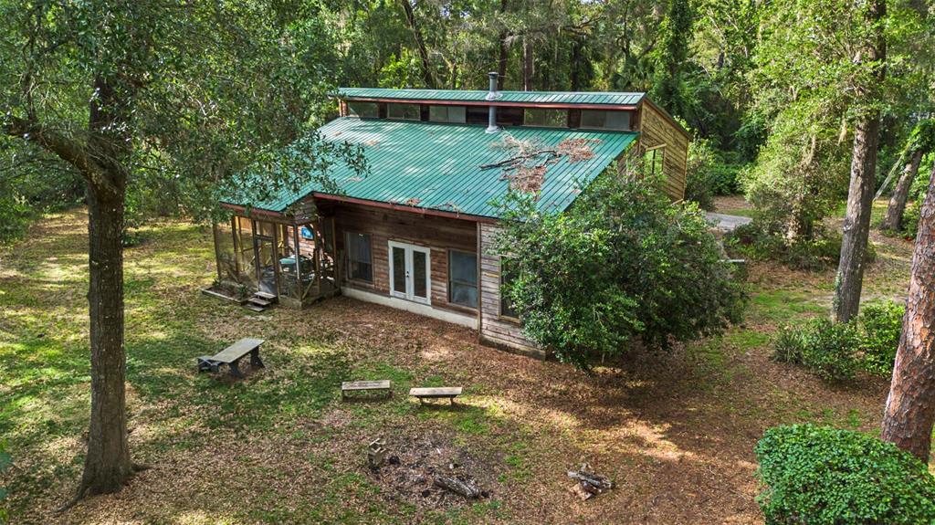 An aerial view of a wooden cabin with a green metal roof in a forest — 2906 SE 36TH LANE, GAINESVILLE, FL