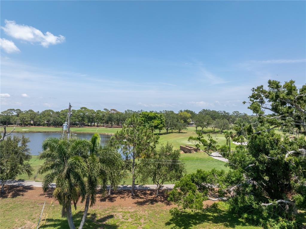 An elevated view of a golf course with a pond, trees, and a stone bridge — 167 ALMEDO WAY NE, ST PETERSBURG, FL