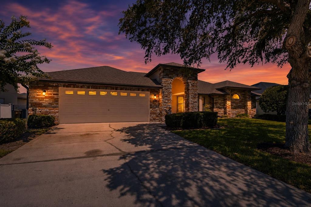 A single-story house with a stone facade, a two-car garage, and a large tree — 122 LENA ANN DRIVE, ST CLOUD, FL