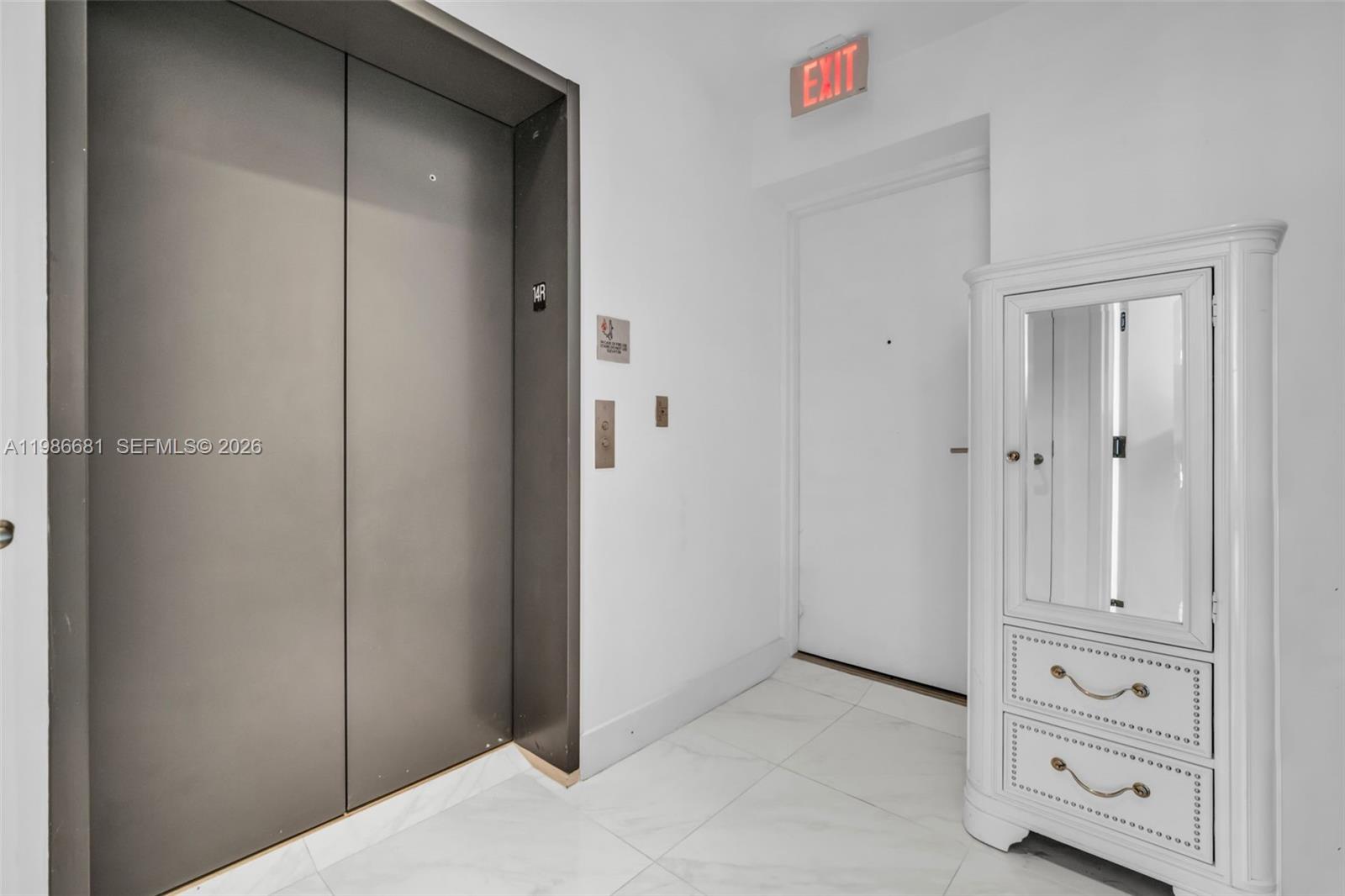 A hallway features a metal elevator door, a white exit door, and a mirrored cabinet — 2900 NE 7th Ave # 1408, Miami FL 33137, MIAMI, FL