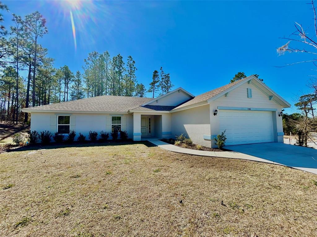 A single-story house with a white exterior, a two-car garage, and a front walkway — 1586 W GAINSBORO LANE, CITRUS SPRINGS, FL