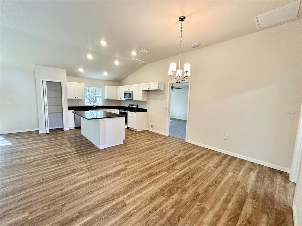 A kitchen with white cabinets, a dark island, and wood-look flooring in an open room — 1586 W GAINSBORO LANE, CITRUS SPRINGS, FL