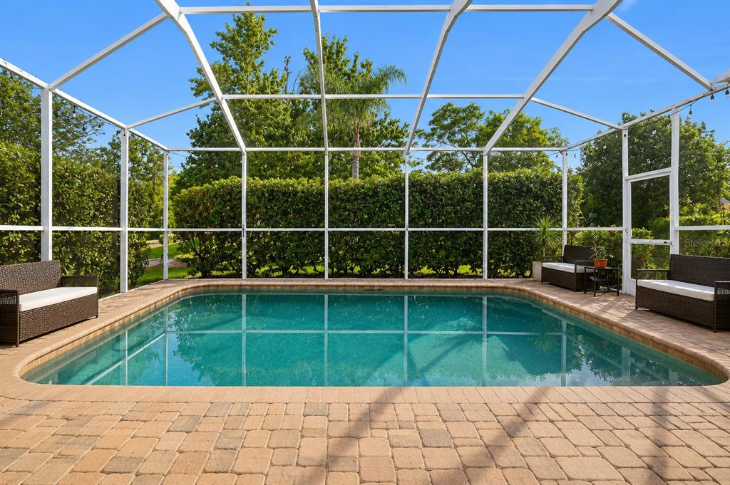 A screened-in swimming pool with a brick paver deck and outdoor seating — 12213 ROSELAND DRIVE, NEW PORT RICHEY, FL