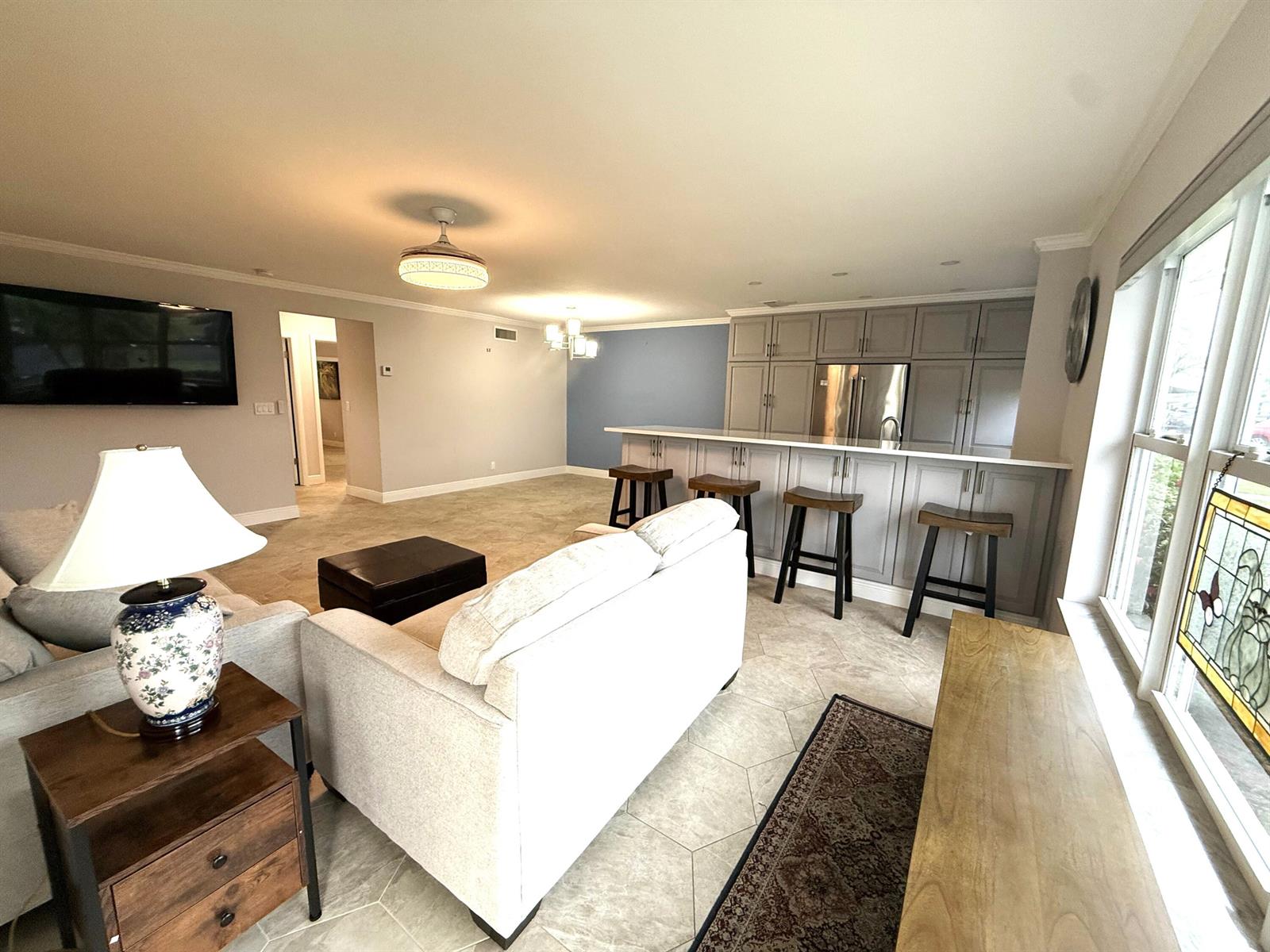 An open-concept living room features a kitchen island with bar stools and tile flooring — 916 Savannas Point Drive, Fort Pierce FL 34982, FORT PIERCE, FL