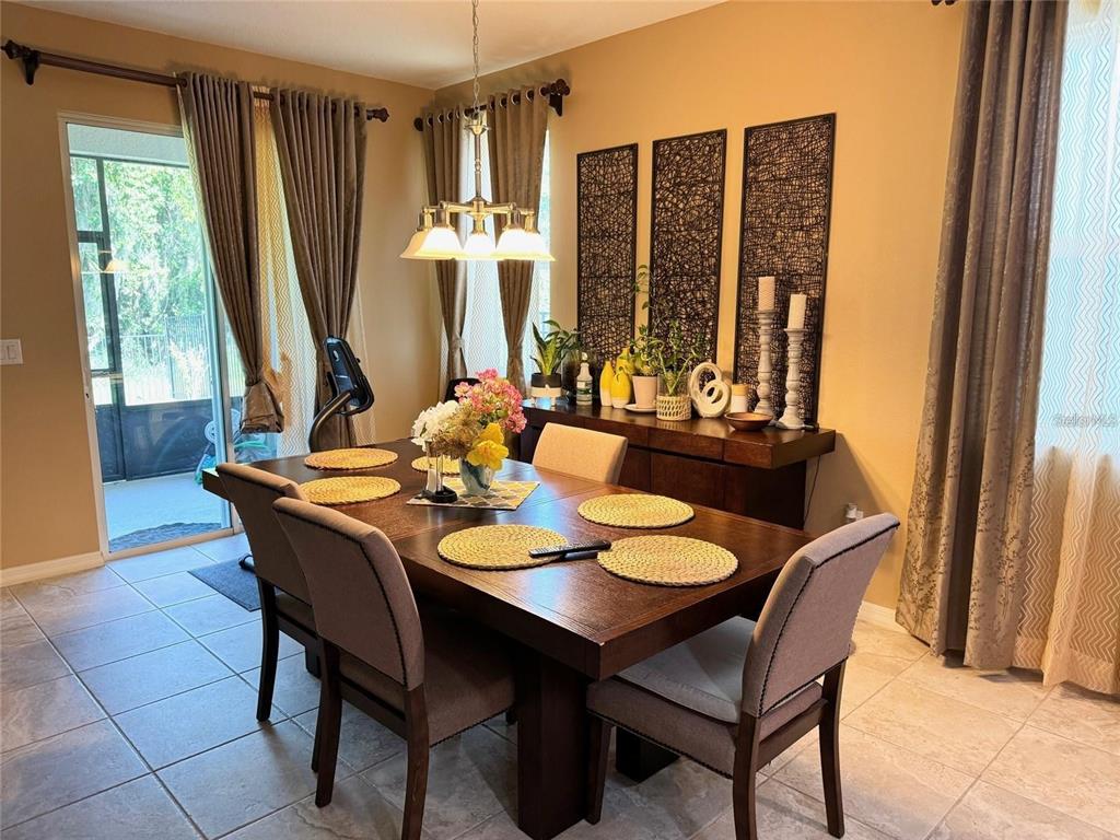 A dining room features a dark wood table, six chairs, a sideboard, and sliding glass doors — 11460 WAKEWORTH STREET, ORLANDO, FL