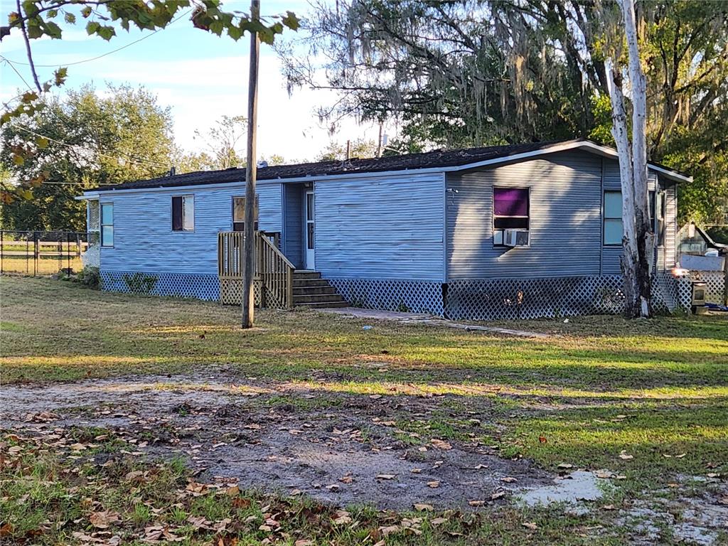 A single-story manufactured home with blue siding and a wooden entrance deck — 2608 20 MILE LEVEL ROAD, LAND O LAKES, FL