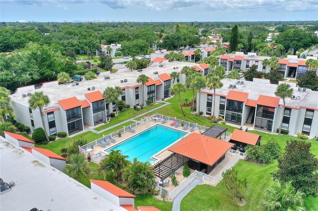 An aerial view of a multi-story apartment complex with a central swimming pool and cabana — 3215 BENEVA ROAD UNIT 204, SARASOTA, FL