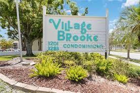A sign for Village Brooke Condominiums stands in a landscaped area with trees and shrubs — 3215 BENEVA ROAD UNIT 204, SARASOTA, FL