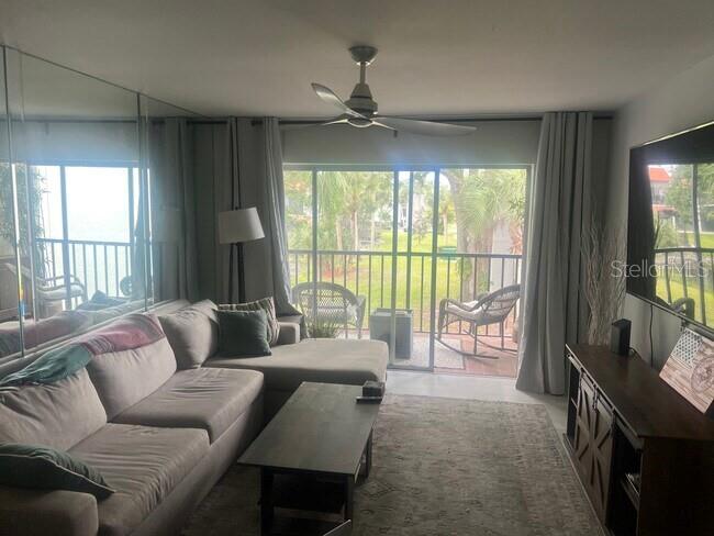 A living room features a sectional sofa, coffee table, ceiling fan, and sliding glass balcony doors — 3215 BENEVA ROAD UNIT 204, SARASOTA, FL