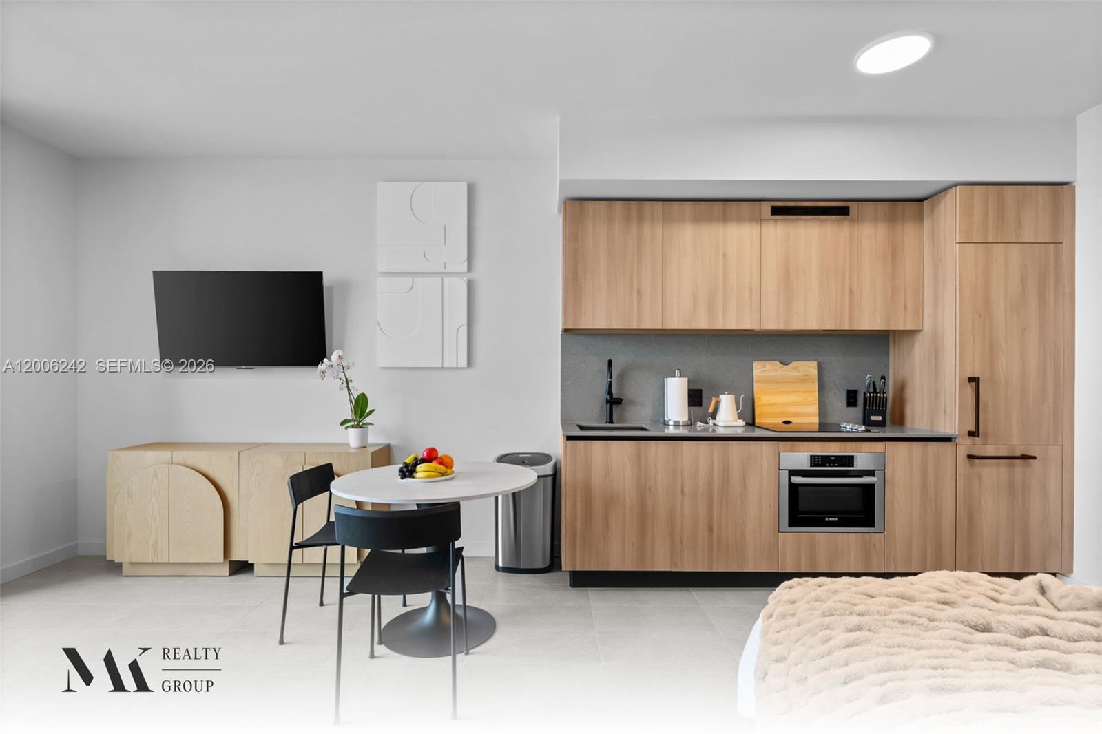 A modern studio apartment features a kitchenette with light wood cabinets and a dining area — 121 NE 5 # 2700, Miami FL 33132, MIAMI, FL