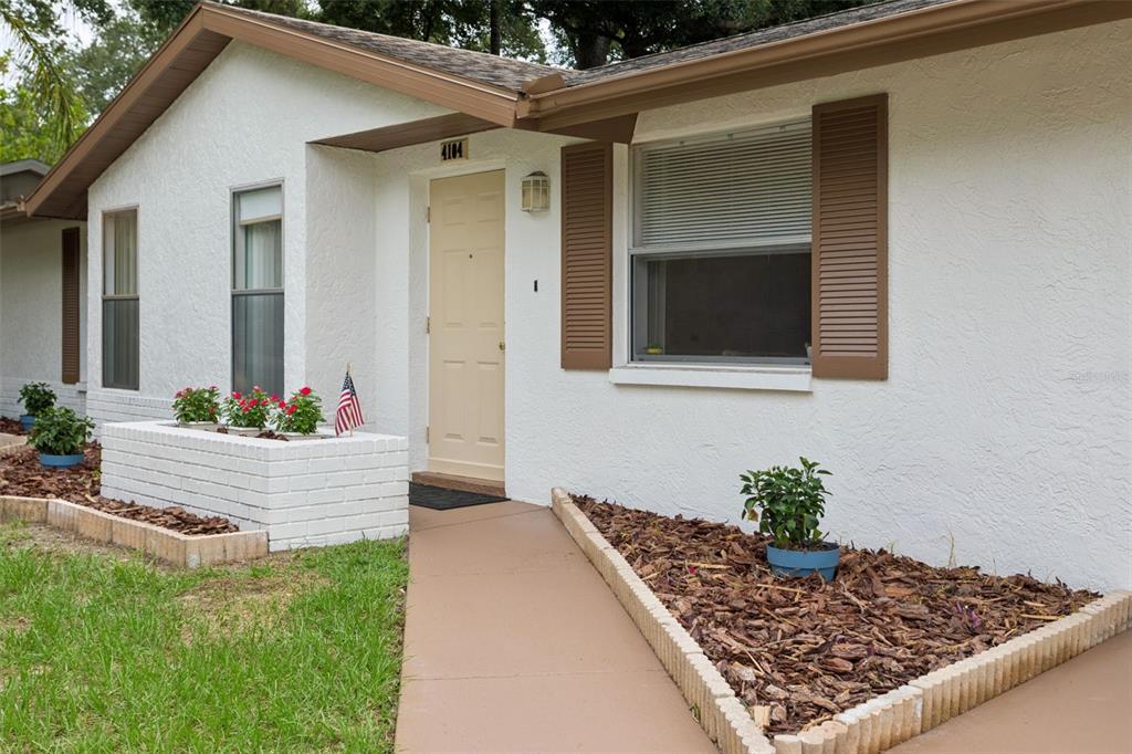 A white stucco house exterior features a tan front door, brown shutters, and brick planters — 4104 N BAY HILLS BOULEVARD, SAFETY HARBOR, FL