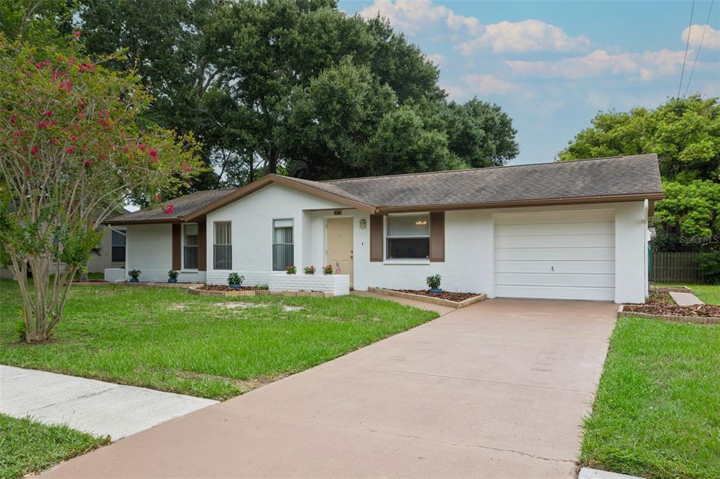 A single-story white house with a brown roof, attached garage, and a front lawn — 4104 N BAY HILLS BOULEVARD, SAFETY HARBOR, FL