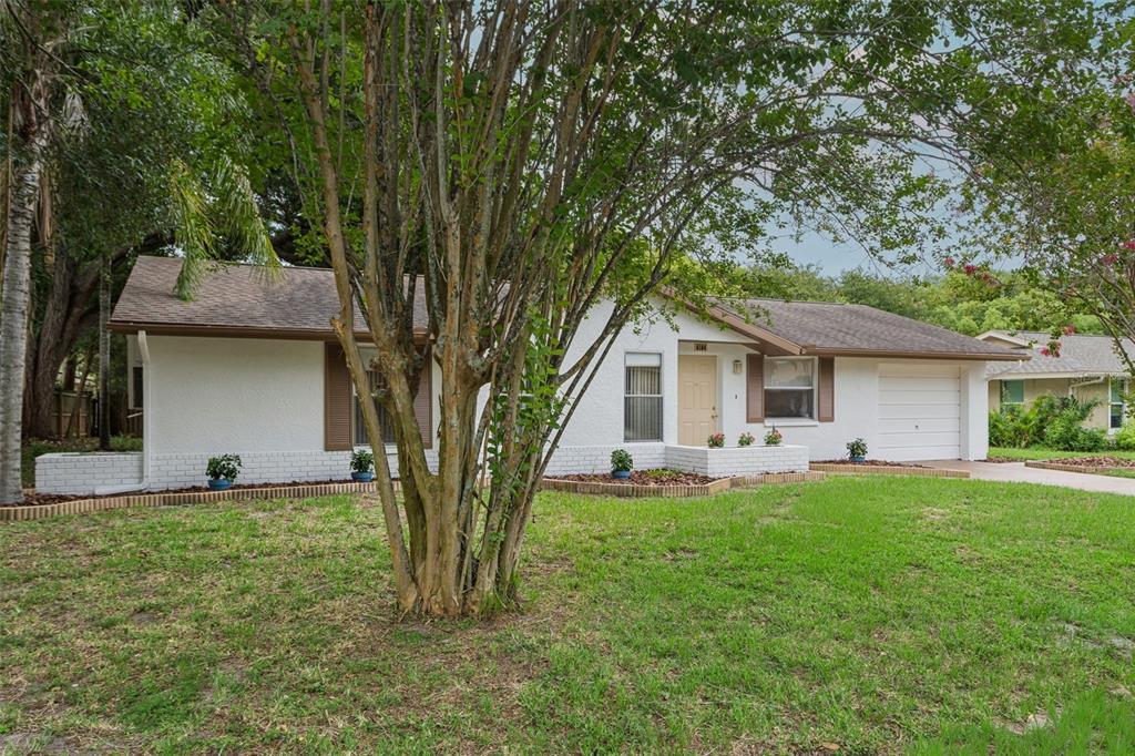 A white, single-story house with a brown roof, garage, and a large tree in front — 4104 N BAY HILLS BOULEVARD, SAFETY HARBOR, FL