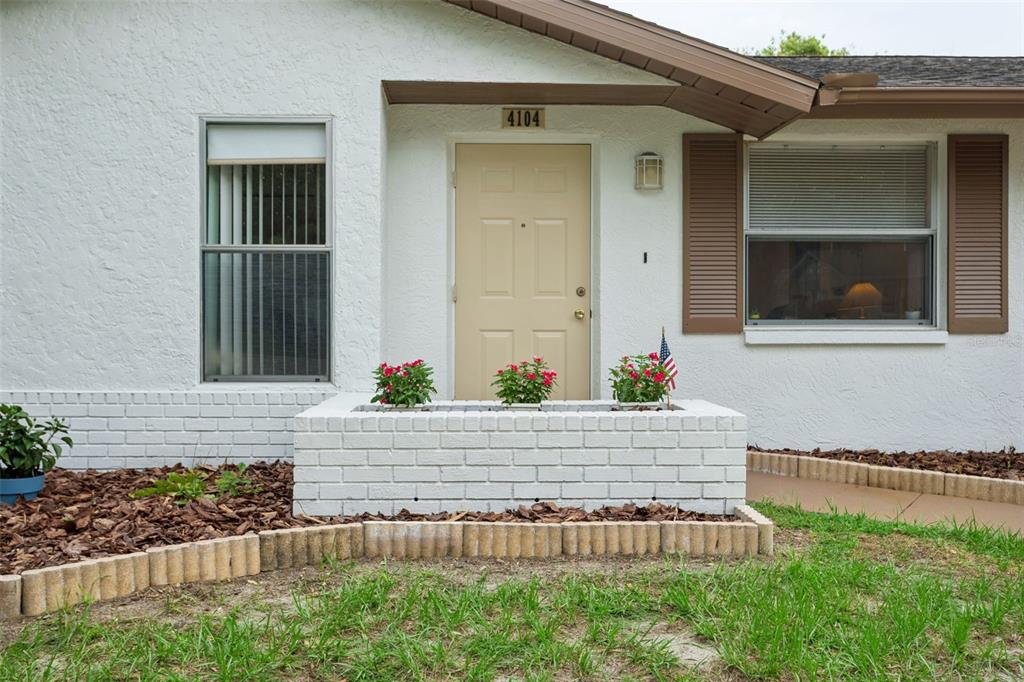 The exterior of a white house features a tan front door and a brick planter — 4104 N BAY HILLS BOULEVARD, SAFETY HARBOR, FL