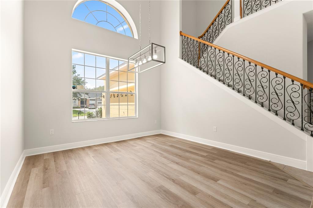 An empty dining area with light wood floors, a tall arched window, and a staircase — 3542 WIND RIVER RUN, CLERMONT, FL
