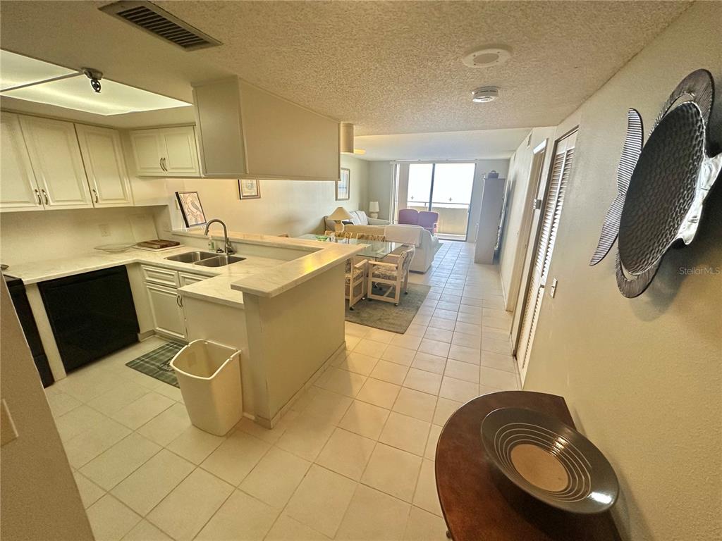 A kitchen with white cabinets and a breakfast bar overlooks a living area with balcony access — 6035 SEA RANCH DRIVE UNIT 508, HUDSON, FL